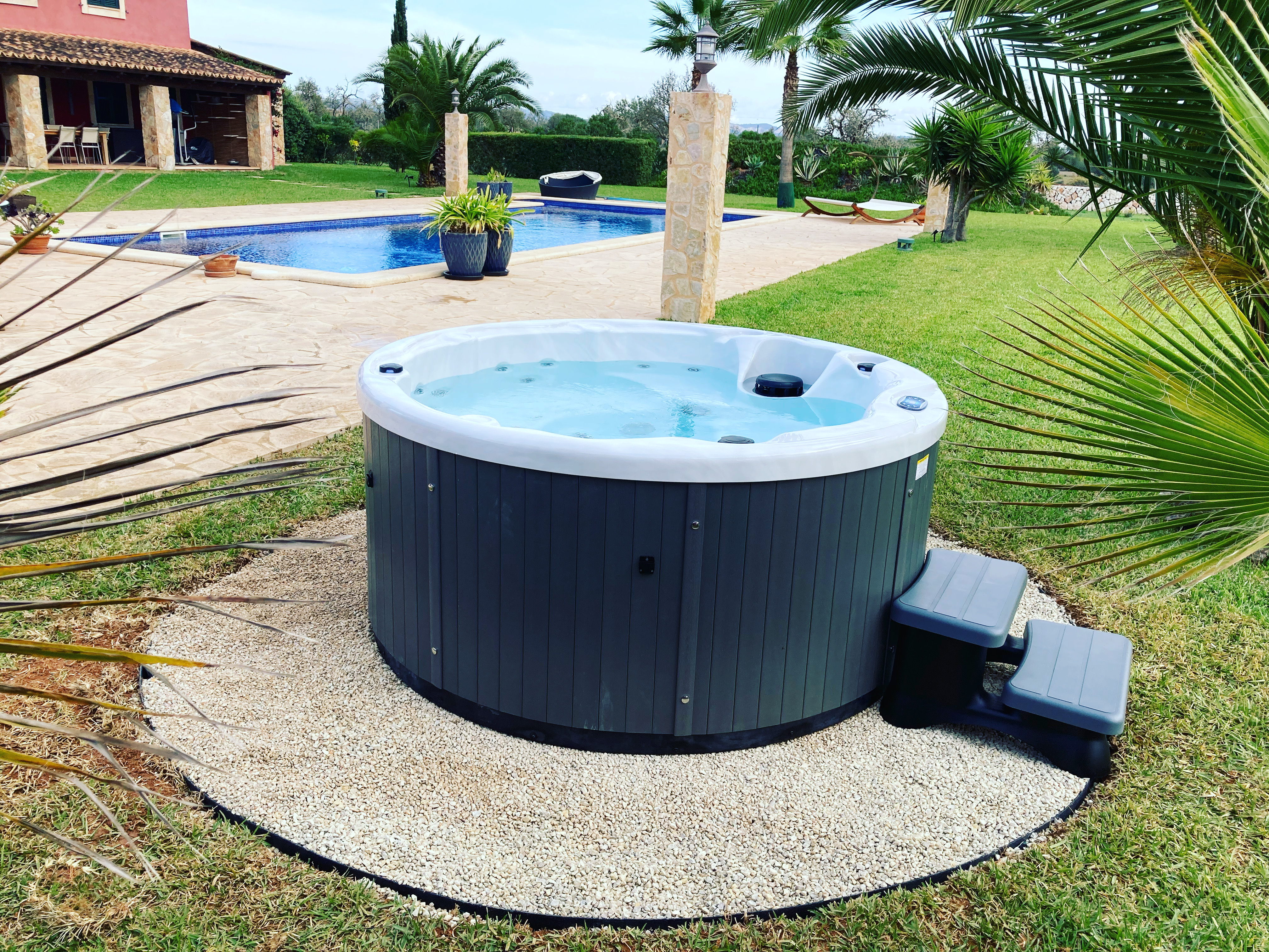 Round hot tub by pool with palm tree, Mallorca villa garden